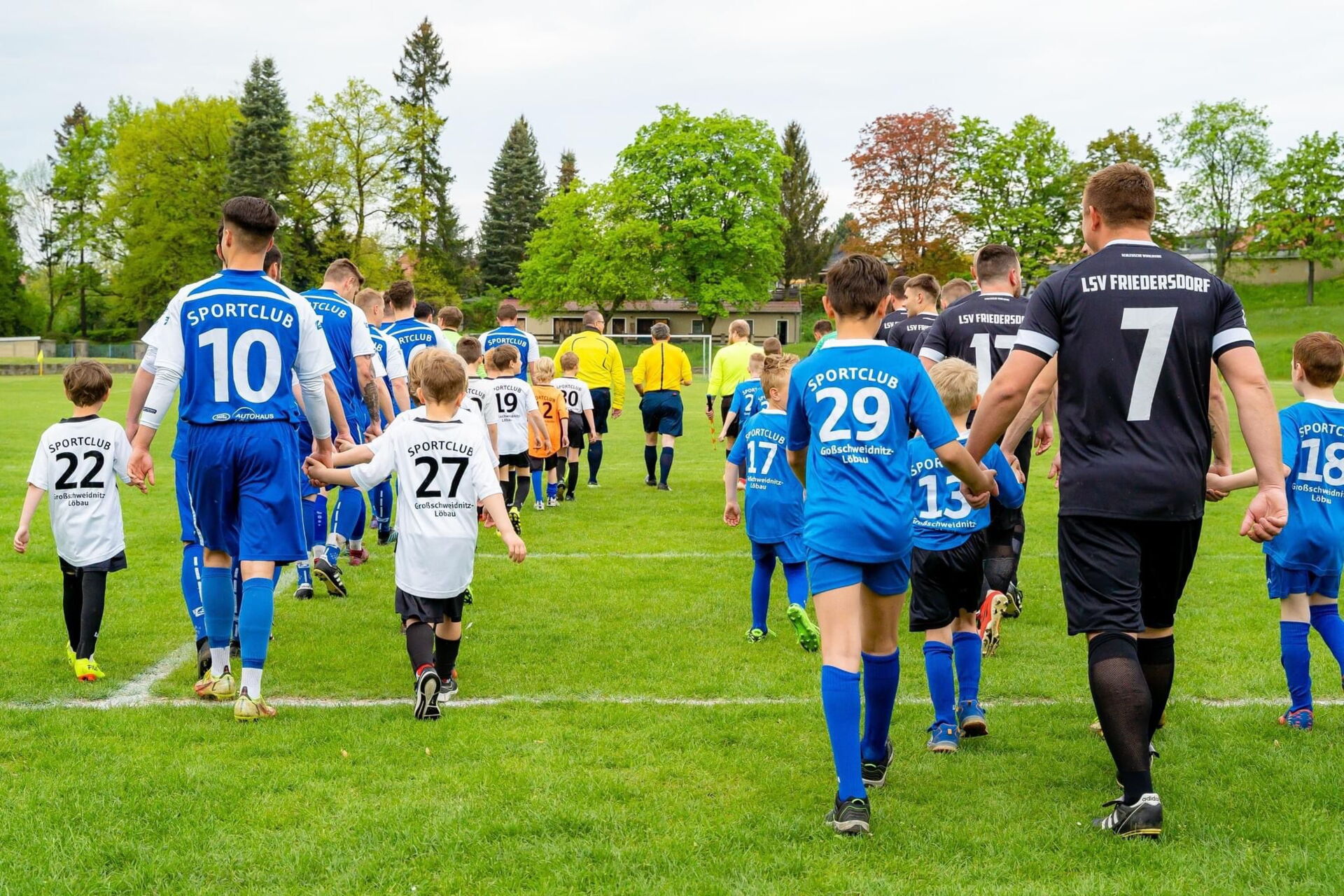 Spieler und Kinder des Sportclub Großschweidnitz - Löbau e.V. laufen auf den Fußballplatz ein.