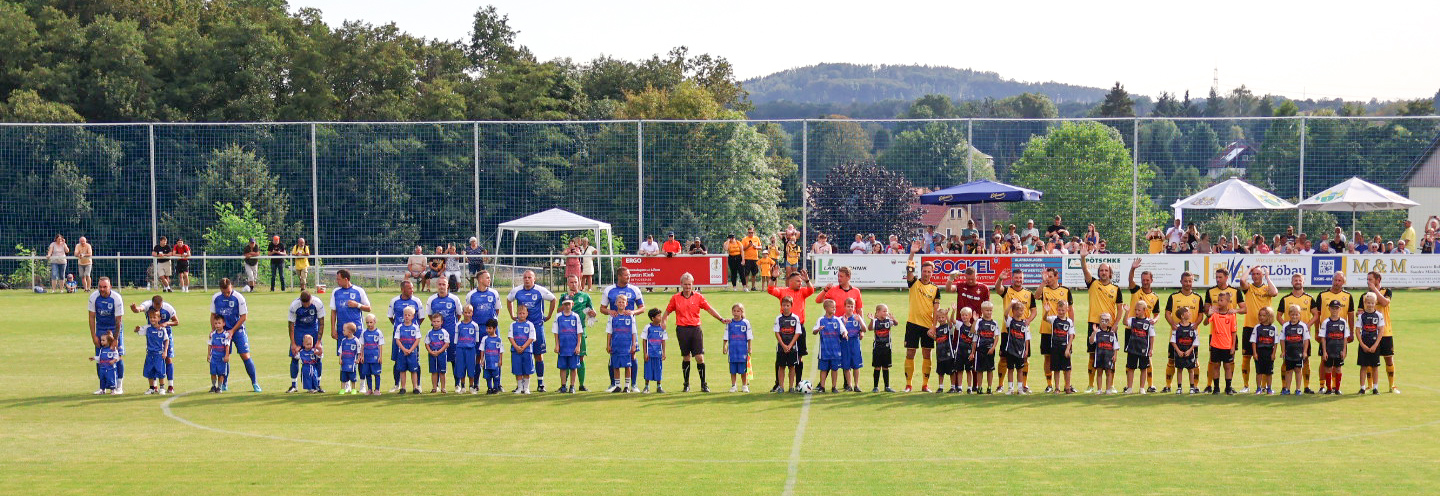 Fußballspieler des Sportclub Großschweidnitz - Löbau e.V. und ihre jungen Fans stehen auf dem Feld.